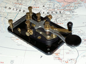 Vintage Morse code telegraph key placed on a map of the United States.
